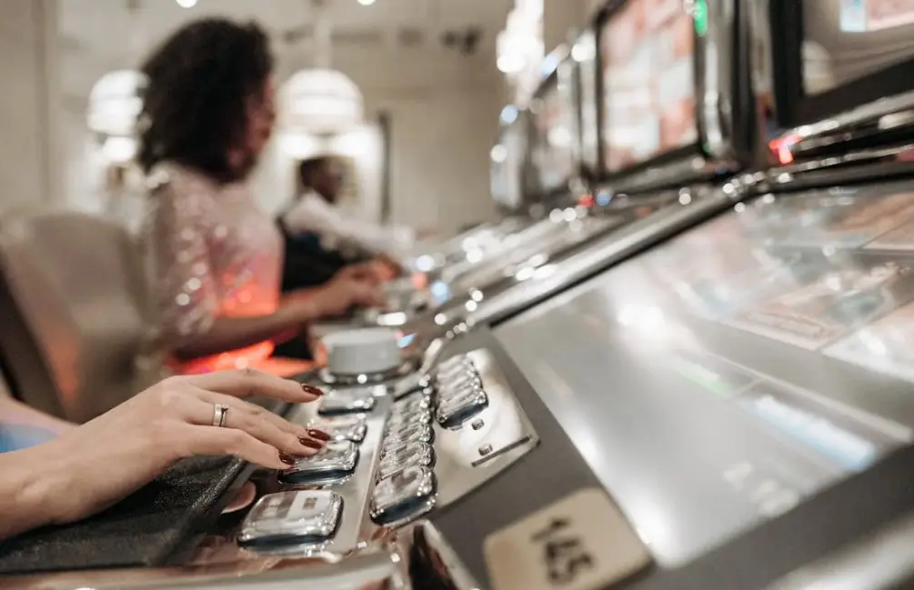 A Person with Manicured Nails Pressing Buttons on a Slot Machine
