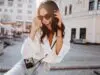 Glad young woman with black wavy hair laughing on the street. Outdoor shot of cute girl in sunglasses posing with camera.
