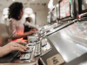 A Person with Manicured Nails Pressing Buttons on a Slot Machine