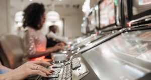 A Person with Manicured Nails Pressing Buttons on a Slot Machine