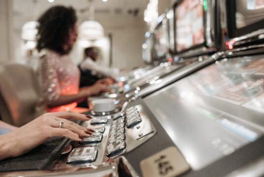A Person with Manicured Nails Pressing Buttons on a Slot Machine