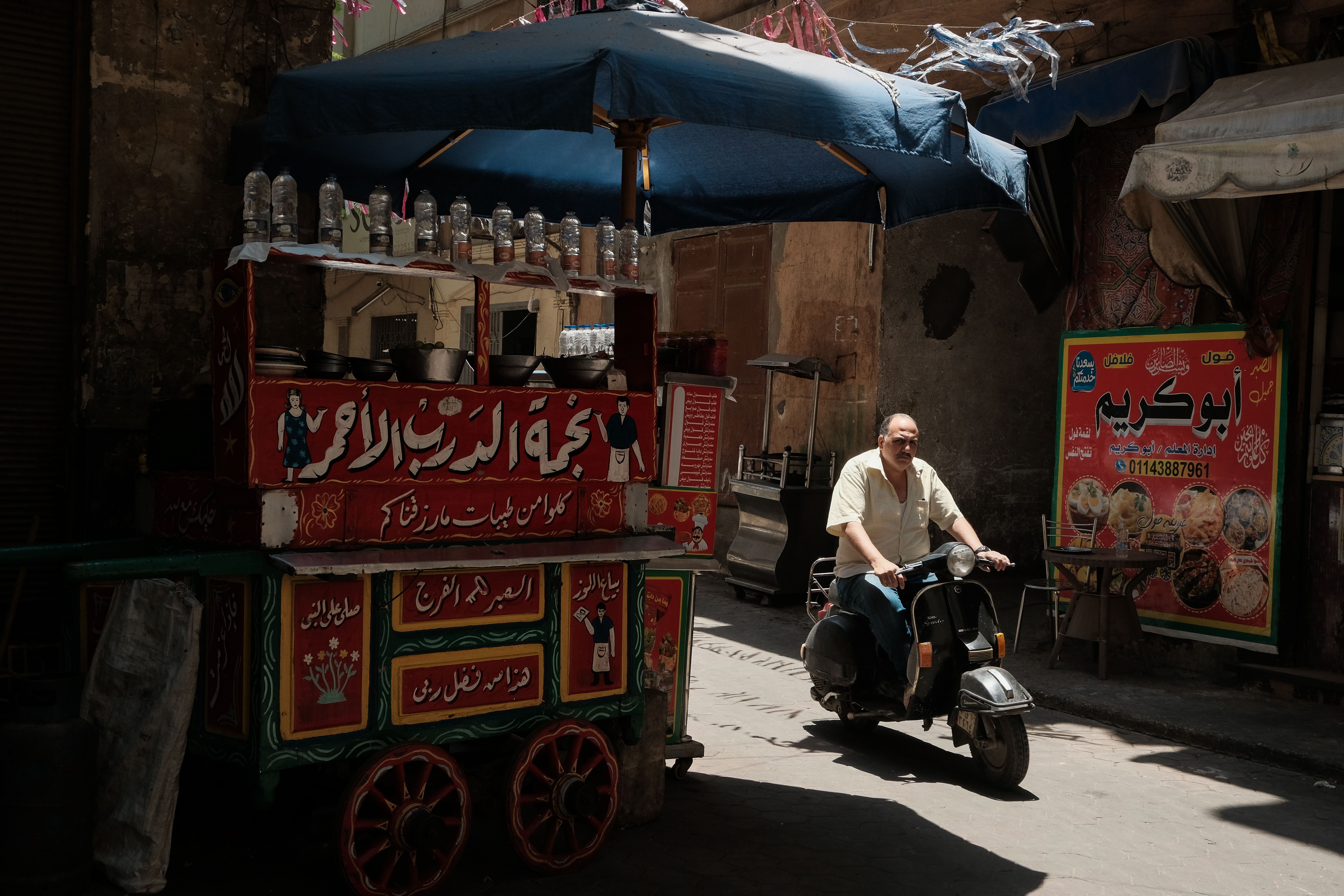 A Cairo street food cart and scooter in a lively city alley, illustrating modern everyday life in Egypt.